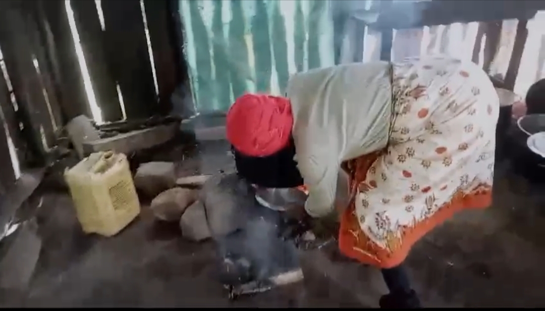 a cook in a red headdress bending over a pile of rocks in the kitchen 